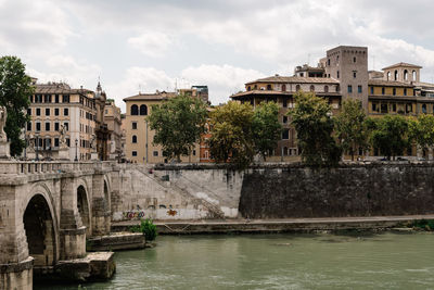 Arch bridge over river against cloudy sky