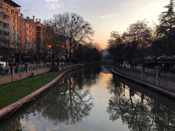Canal amidst city against sky during sunset