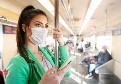 Portrait of young woman holding while sitting in bus