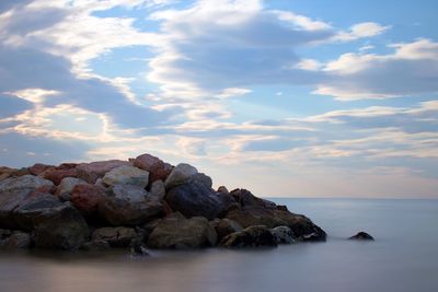 Rocks by sea against sky