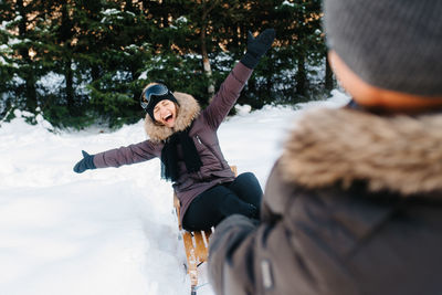 Full length of woman with arms raised in snow