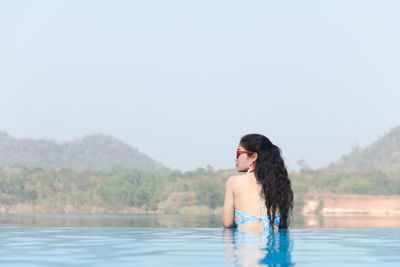 Young woman in infinity pool against clear sky