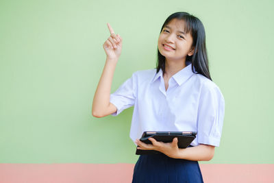 Young woman smiling while standing against wall