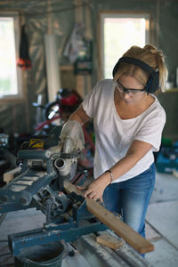 Woman cutting wood with circular saw during home improvement