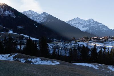 Scenic view of village with snowcapped mountains against sky