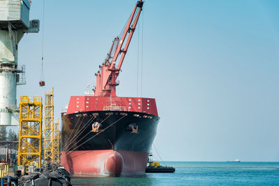 Cranes at commercial dock against clear sky