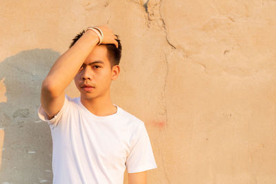 Portrait of young man looking away against wall