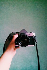 Close-up of hand holding camera against wall