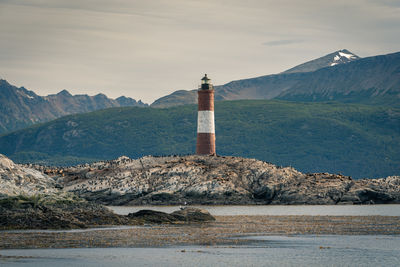 Lighthouse by sea against sky