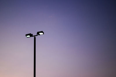 Silhouette of illuminated floodlight against sky