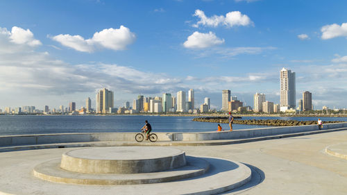 Man riding by city against sky