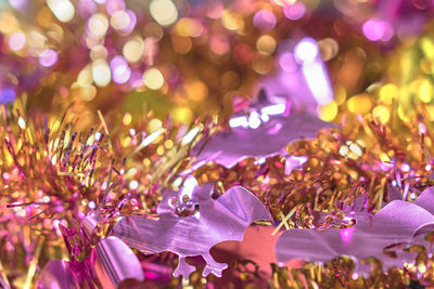 Background texture full of bokeh with garlands decorated by funny purple bats smiling faces.