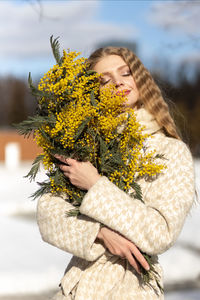 A  woman with a yellow acacia flowers. the concept of the spring - march 8, easter, women's day