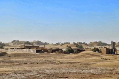 Houses on field against clear blue sky