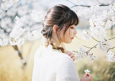 Woman standing by cherry blossom