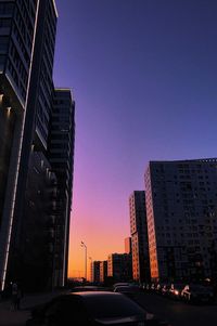 City street and buildings against sky during sunset