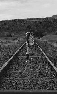 Rear view of woman walking on railroad track