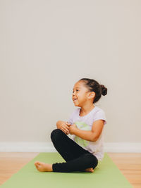 Cute girl sitting on wooden wall