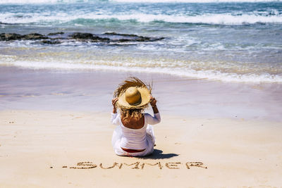 Rear view of woman sitting on beach