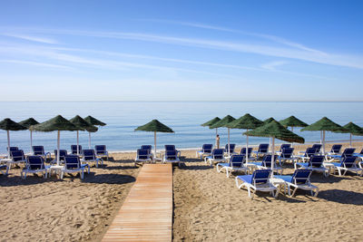 Chairs on beach against blue sky