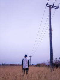 Rear view of man on field against clear sky