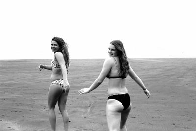 Full length of young woman on beach against sky