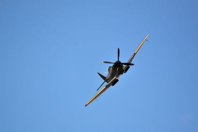 Low angle view of plane against clear blue sky