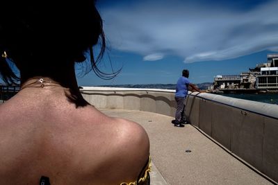 Rear view of people on beach against sky