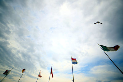 Low angle view of flags flying against sky