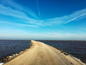 Road by sea against blue sky