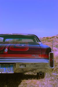 Vintage car on field against clear blue sky