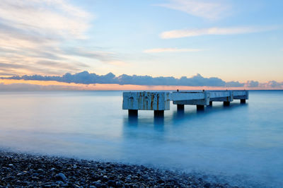 Pier on sea against sky during sunset