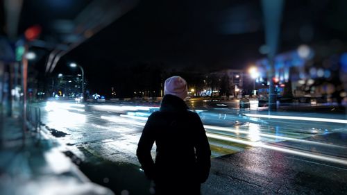 Rear view of man standing in city at night