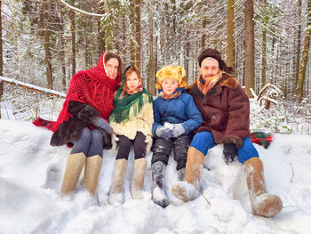 Portrait of smiling friends sitting on snow