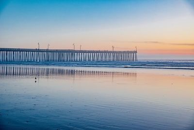 Pier on sea against clear sky at sunset