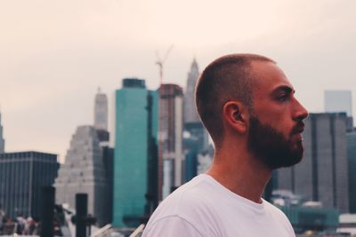 Portrait of young man against modern buildings in city