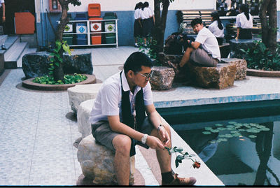 Full length of young man sitting outdoors