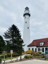 Lighthouse by building against sky