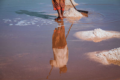 Low section of woman standing on wet beach