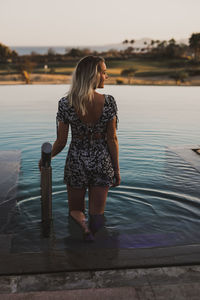 Rear view of woman standing in lake against sky