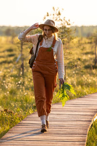 Naturalist woman botanist with backpack on ecological hiking trail in summer outdoors. 