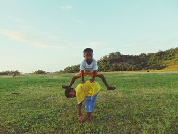 Boy walking on grassy field against sky