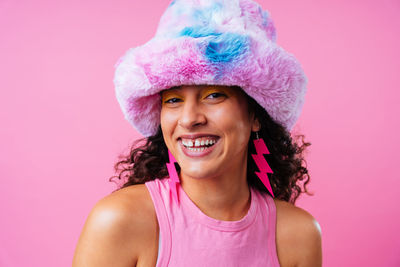 Portrait of young woman wearing hat against pink background