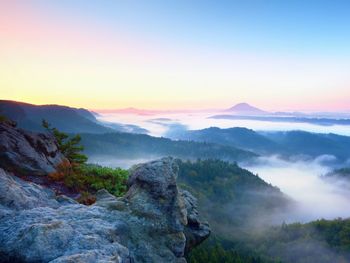 Misty awaking of beautiful fairy valley. peaks of rocks above creamy foggy clouds. fog is shinning .