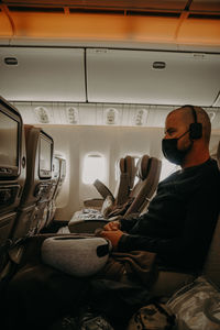 Man seating in the airplane wearing a mask