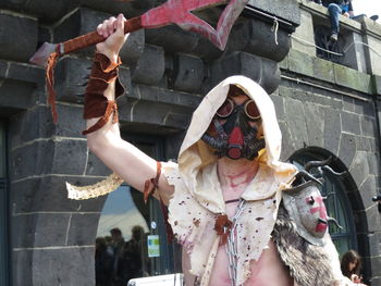 Midsection of woman holding mask with umbrella