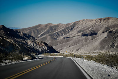 Road by mountain against clear sky