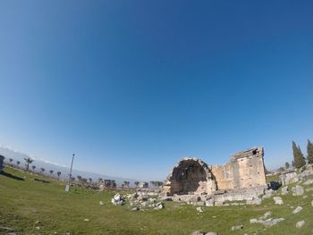 Old ruins on field against clear blue sky