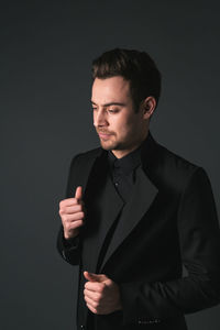 Young man standing against black background