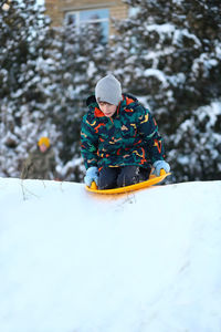 Winter portrait of a boy with a plastic sled sliding on a snowy slope 